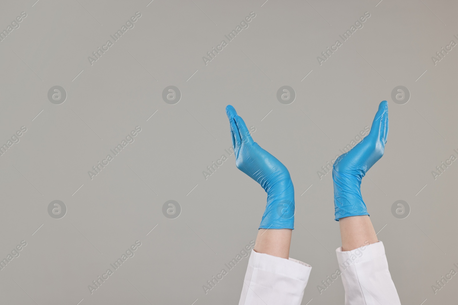 Photo of Doctor holding something on grey background, closeup. Space for text