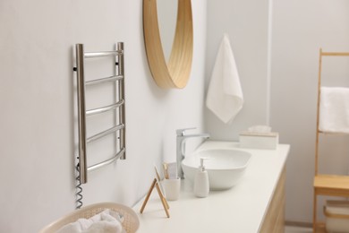 Photo of Heated towel rail on white wall in bathroom