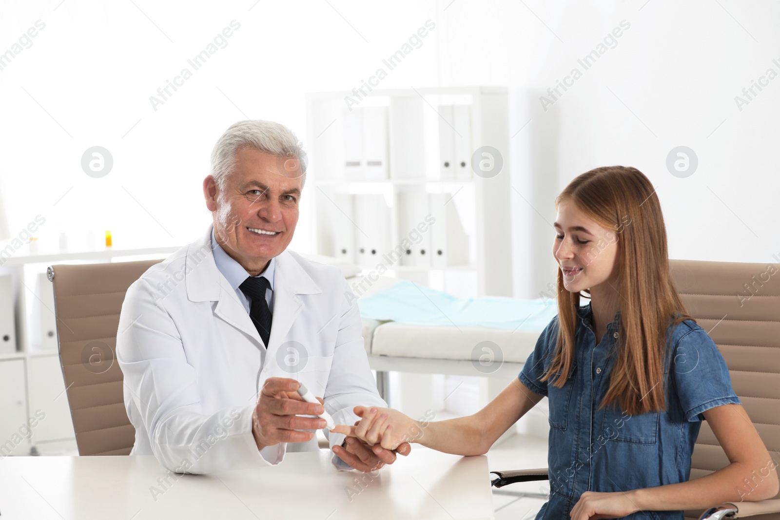 Photo of Doctor taking patient's blood sample with lancet pen in hospital. Diabetes control