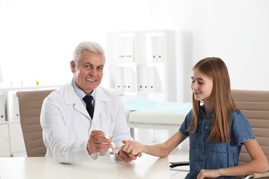 Doctor taking patient's blood sample with lancet pen in hospital. Diabetes control