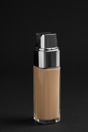Photo of Bottle of foundation on black background. Cosmetic product