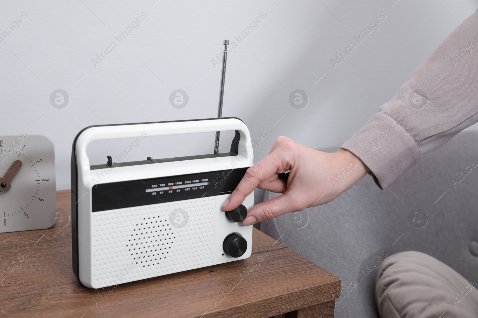 Photo of Woman turning volume knob on radio at home, closeup