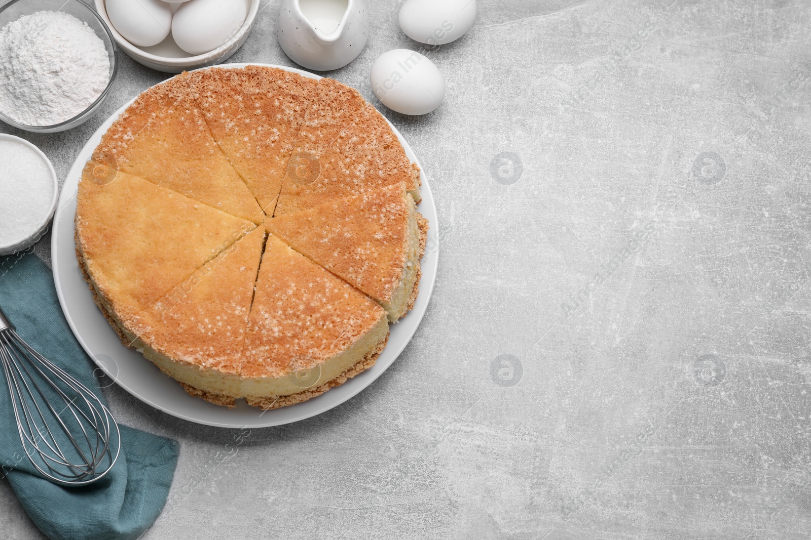 Photo of Pieces of tasty sponge cake, whisk and ingredients on light grey table, flat lay. Space for text