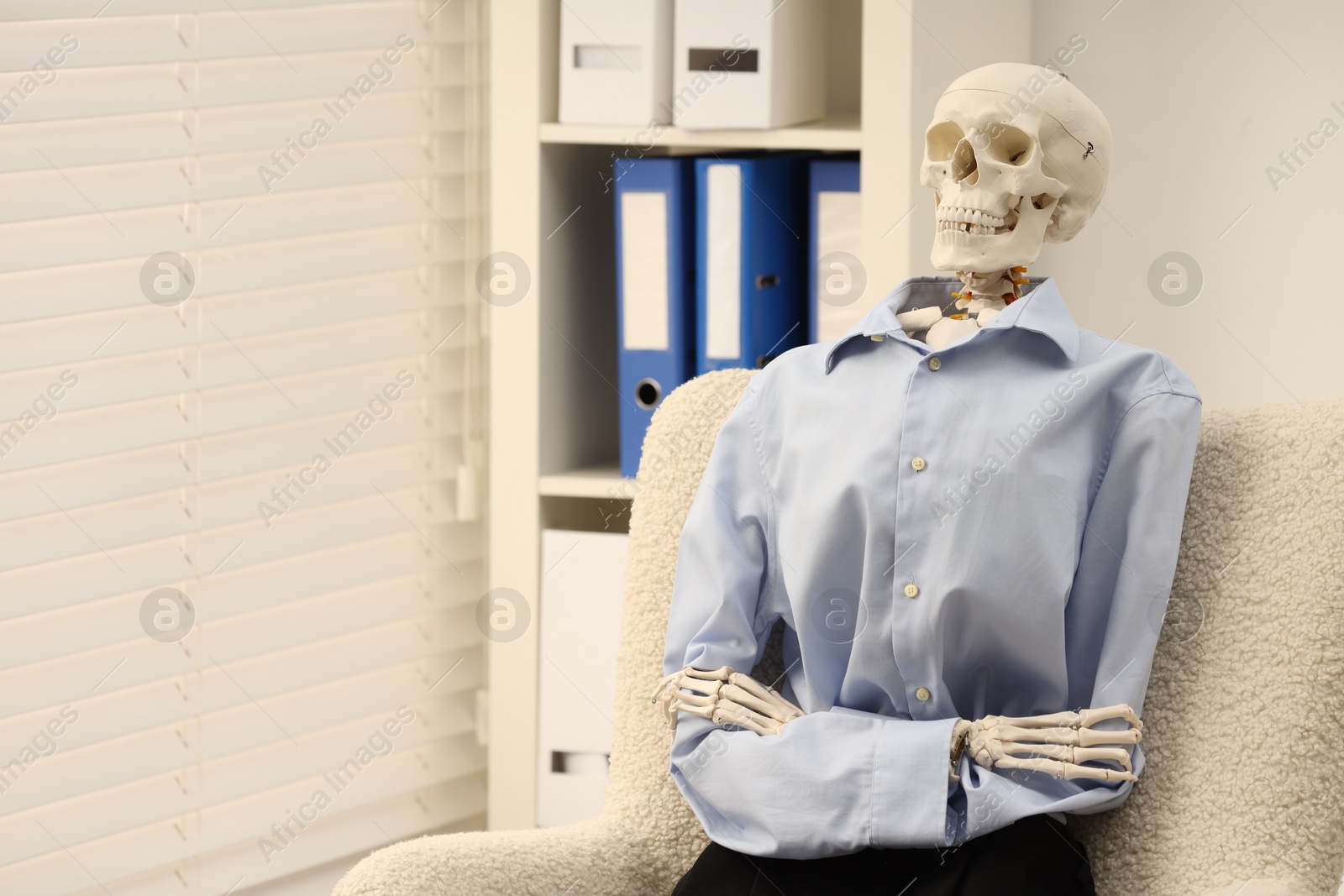 Photo of Waiting concept. Human skeleton sitting in armchair at office, space for text