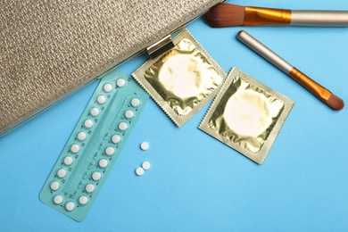 Photo of Flat lay composition with birth control pills and condoms on light blue background. Safe sex concept