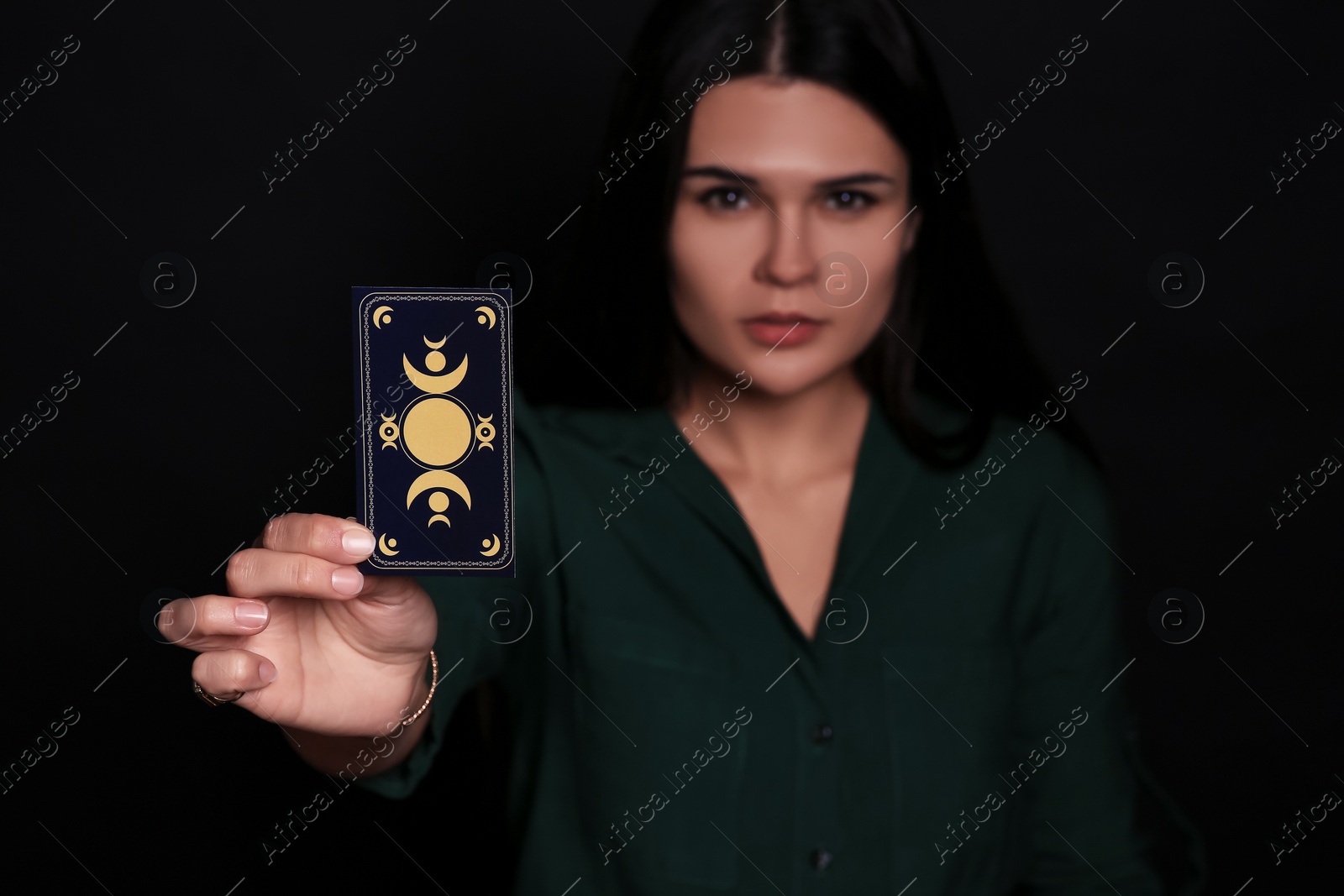 Photo of Soothsayer predicting future against black background, closeup. Focus on tarot card