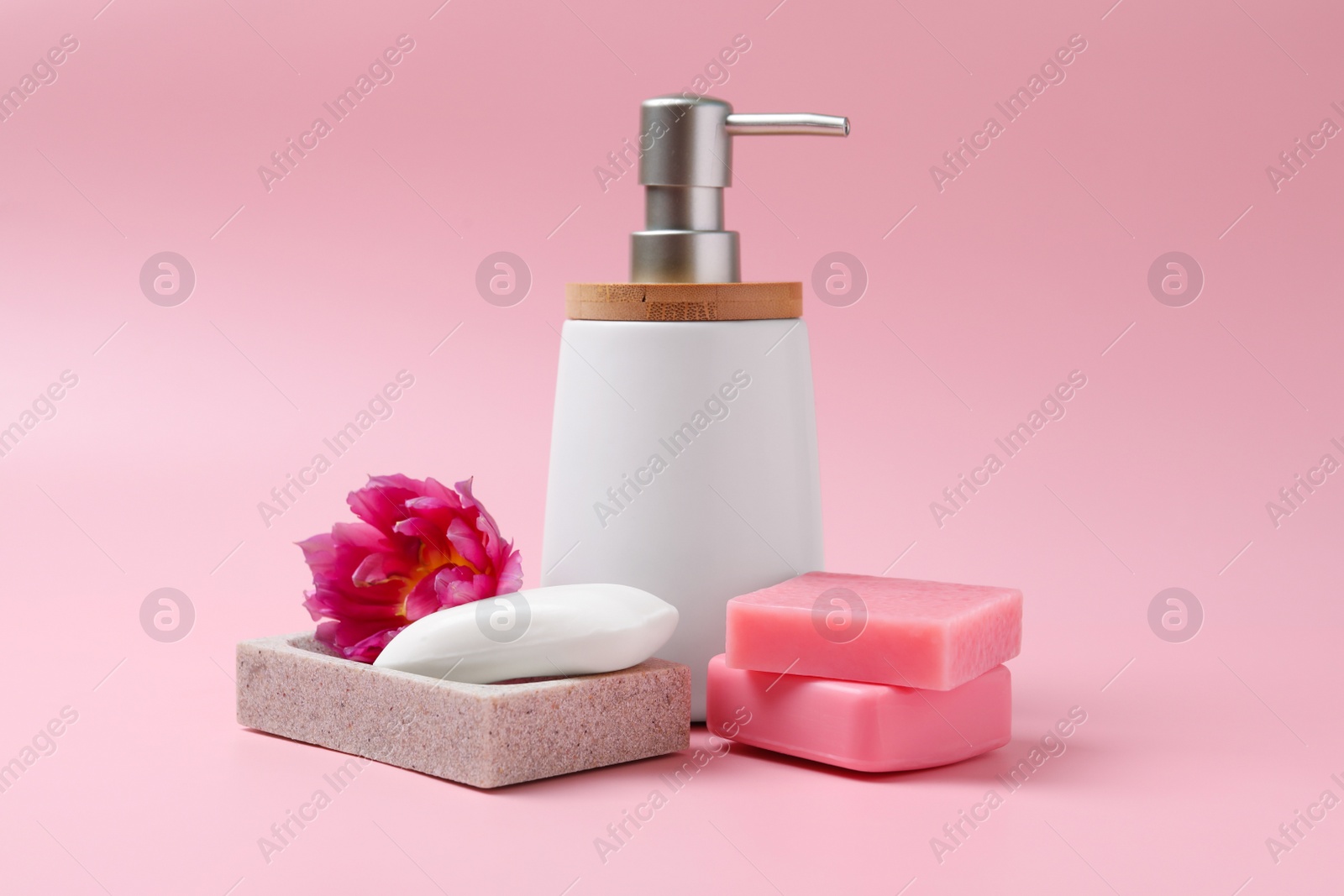 Photo of Soap bar and bottle dispenser on pink background