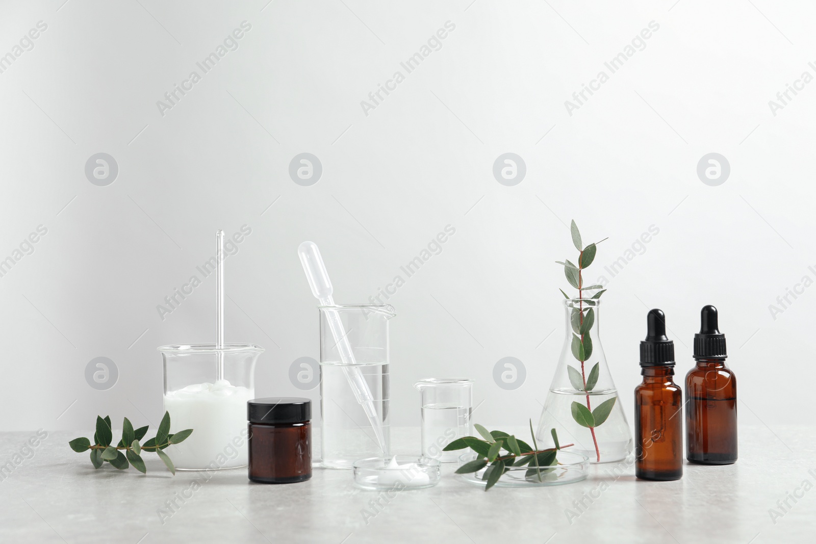 Photo of Natural ingredients for cosmetic products and laboratory glassware on white table