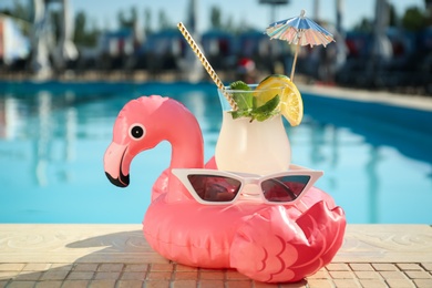 Tasty refreshing cocktail and sunglasses on edge of swimming pool. Party items