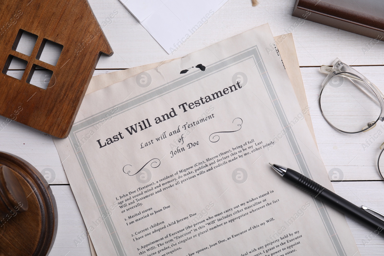 Photo of Last will and testament near house model, glasses, pen on white wooden table, flat lay