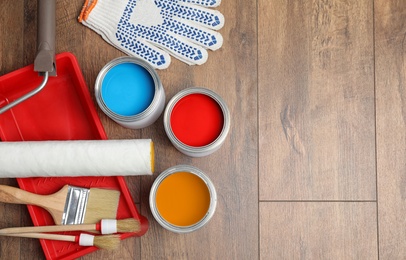 Photo of Flat lay composition with cans of paint and brushes on wooden background. Space for text