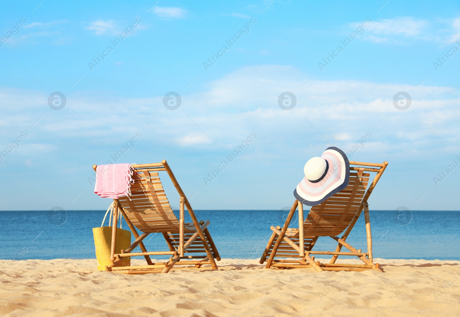 Photo of Empty wooden sunbeds and beach accessories on sandy shore