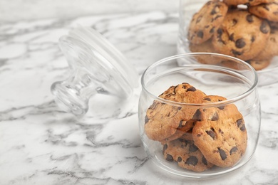 Photo of Jar with chocolate chip cookies on marble background, space for text