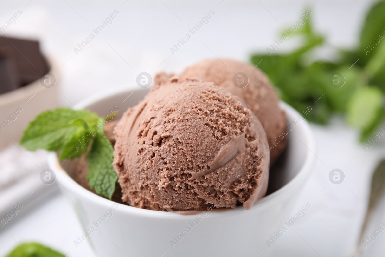 Photo of Bowl with tasty chocolate ice cream and mint leaves on table, closeup