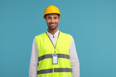 Photo of Engineer with hard hat and badge on light blue background