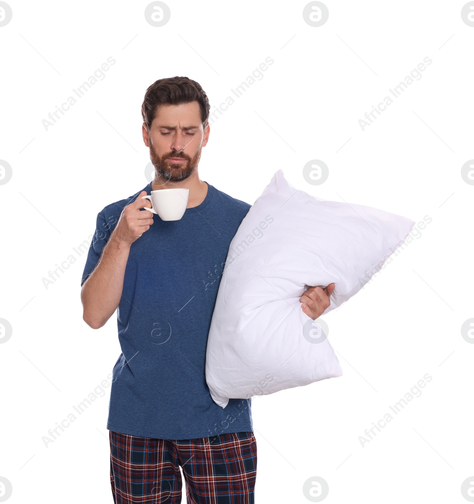 Photo of Tired man with cup of drink and soft pillow on white background