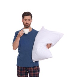 Tired man with cup of drink and soft pillow on white background