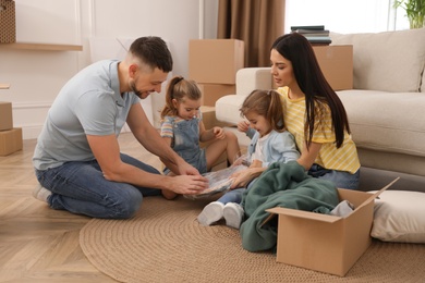 Photo of Happy family unpacking clock at their new house on moving day