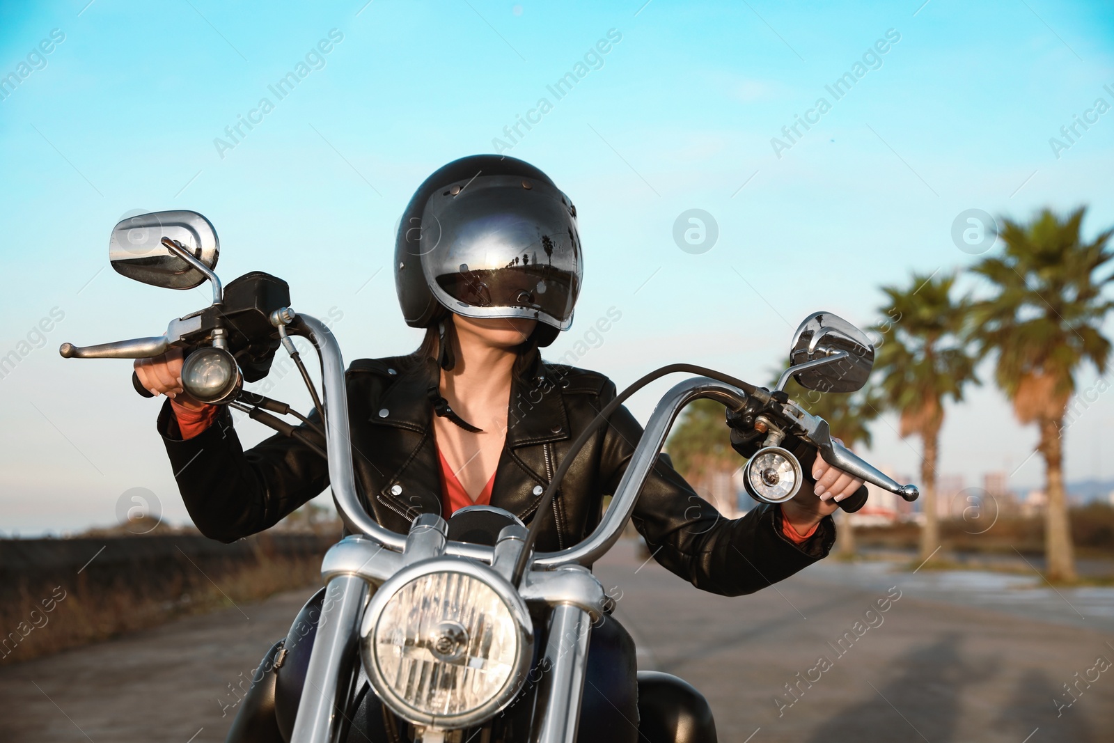 Photo of Woman in helmet riding motorcycle on sunny day