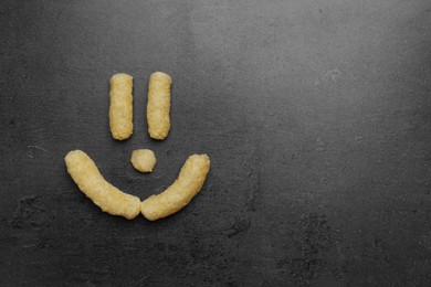 Photo of Funny face made of corn sticks on dark grey table, flat lay. Space for text