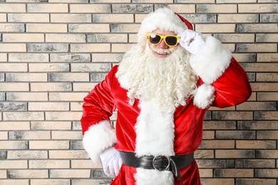 Photo of Authentic Santa Claus wearing sunglasses on brick wall background