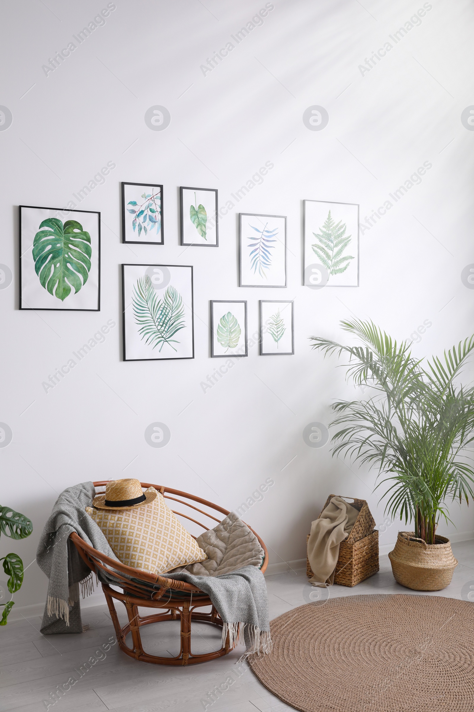 Photo of Beautiful paintings of tropical leaves on white wall in living room interior