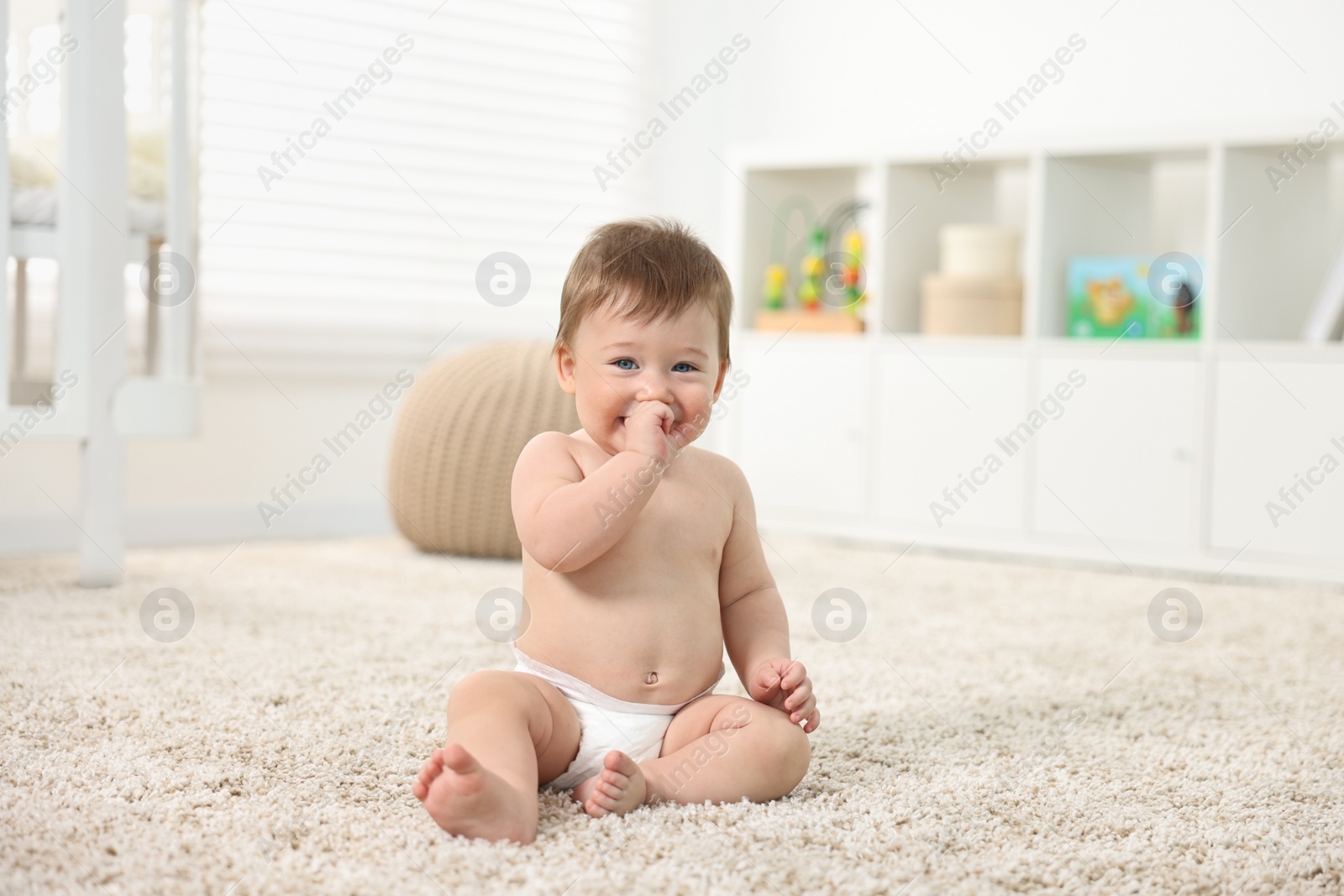 Photo of Cute baby boy sitting on carpet at home