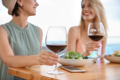 Young women with glasses of wine at table