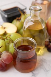 Photo of Different types of vinegar and ingredients on light table, closeup