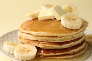 Photo of Delicious pancakes with bananas, honey and butter on beige background, closeup