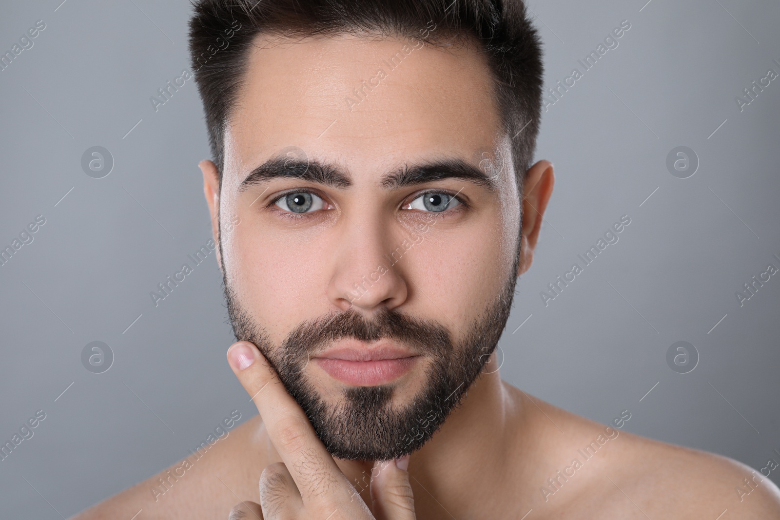Photo of Handsome young man with beard after shaving on grey background, closeup