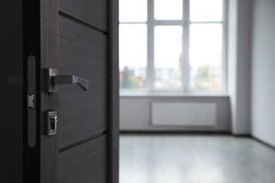 Wooden door open into empty office room, closeup. Space for text