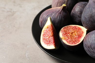 Photo of Whole and cut ripe figs on light grey textured table, closeup. Space for text