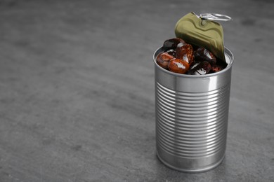 Tin can with kidney beans on gray table, space for text