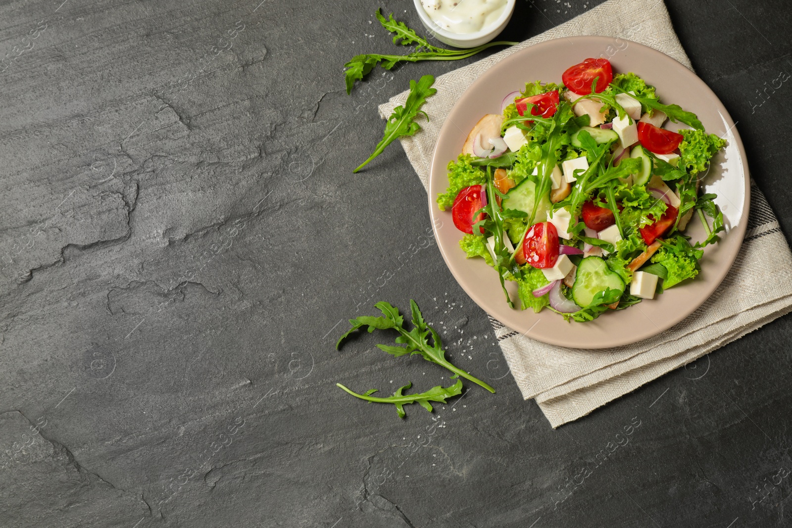 Photo of Delicious salad with meat, arugula and vegetables on black table, flat lay. Space for text