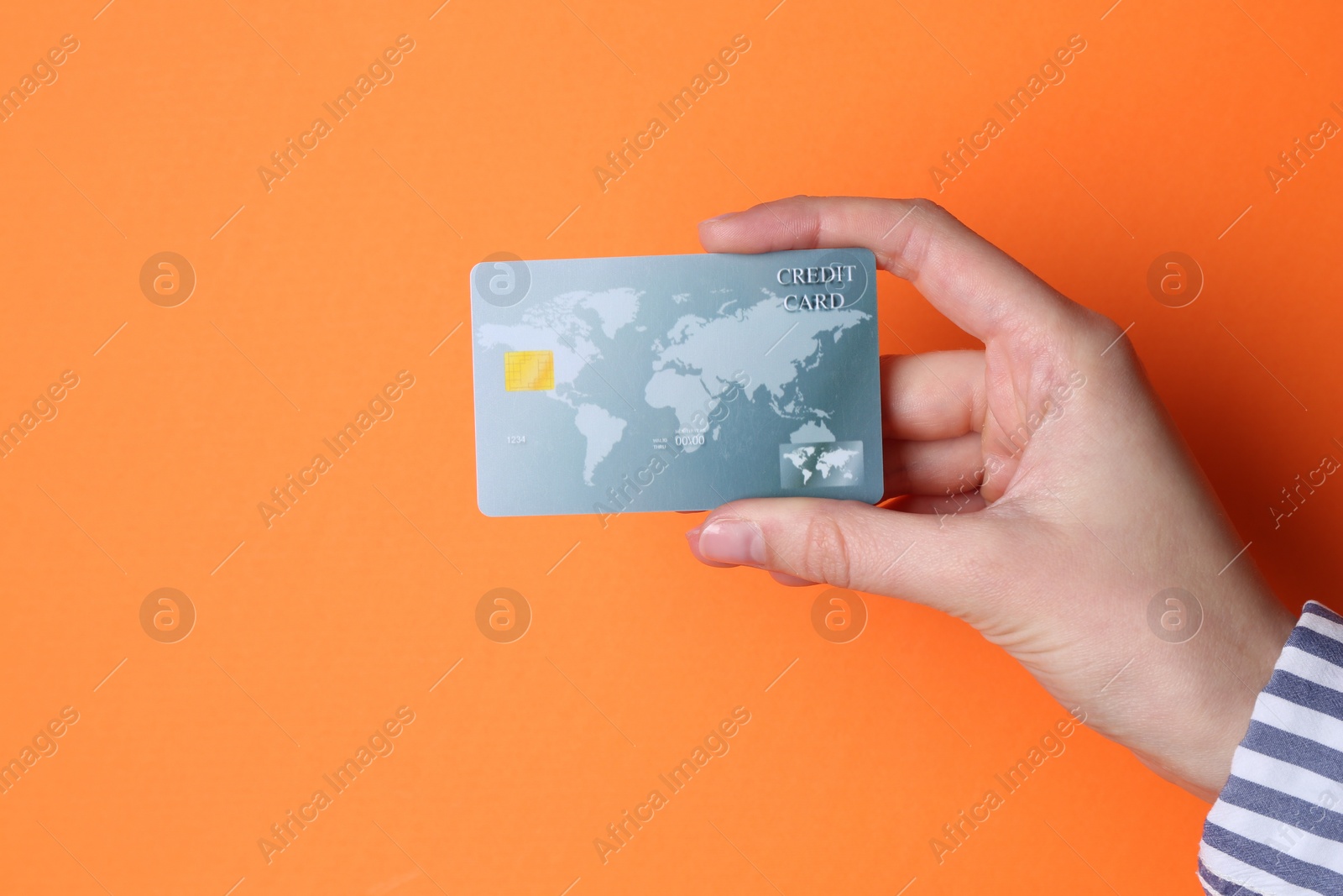 Photo of Woman holding credit card on orange background, closeup