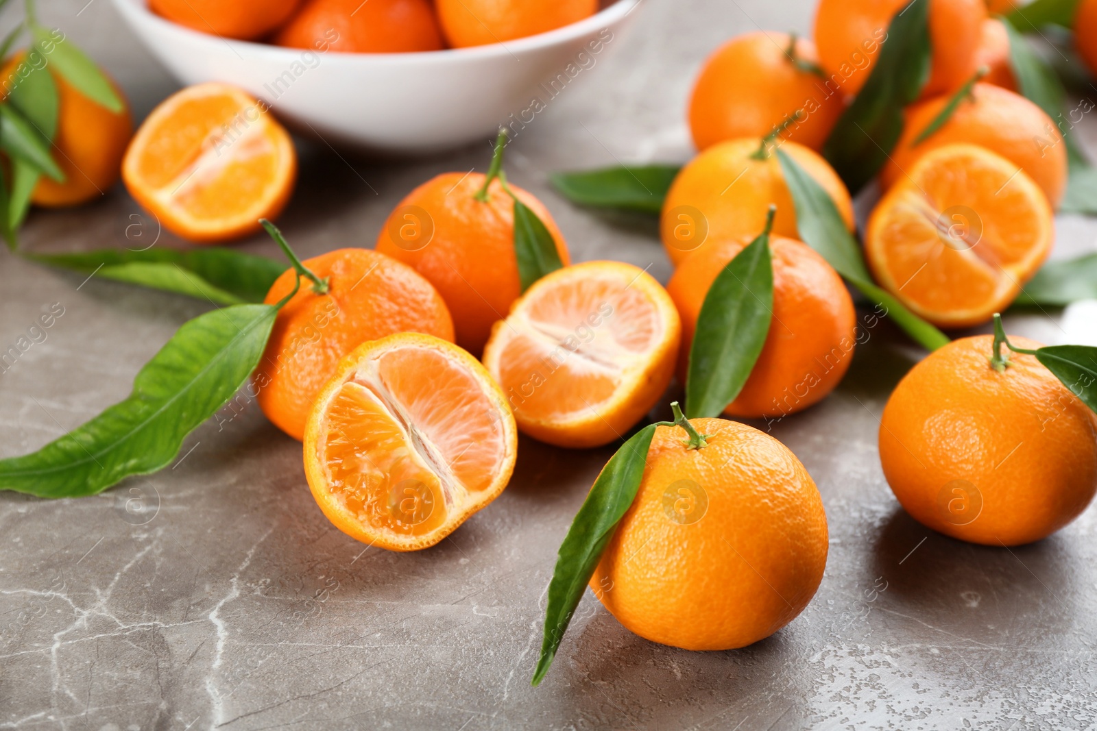 Photo of Fresh tangerines with green leaves on grey table