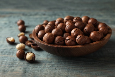 Photo of Plate with organic Macadamia nuts on blue wooden background