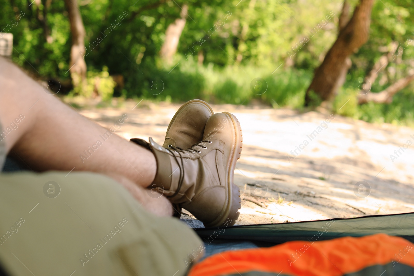 Photo of Young man resting in camping tent at forest, view from inside