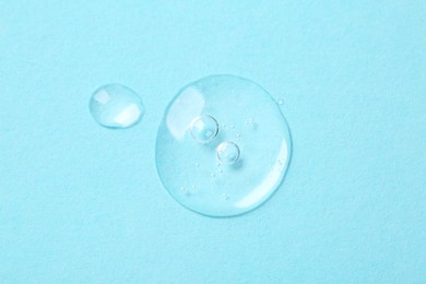 Photo of Samples of cosmetic serum on light blue background, top view