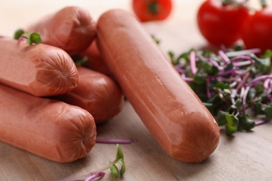 Photo of Tasty vegan sausages and products on white wooden table, closeup