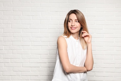 Photo of Portrait of young woman with beautiful face near white brick wall. Space for text