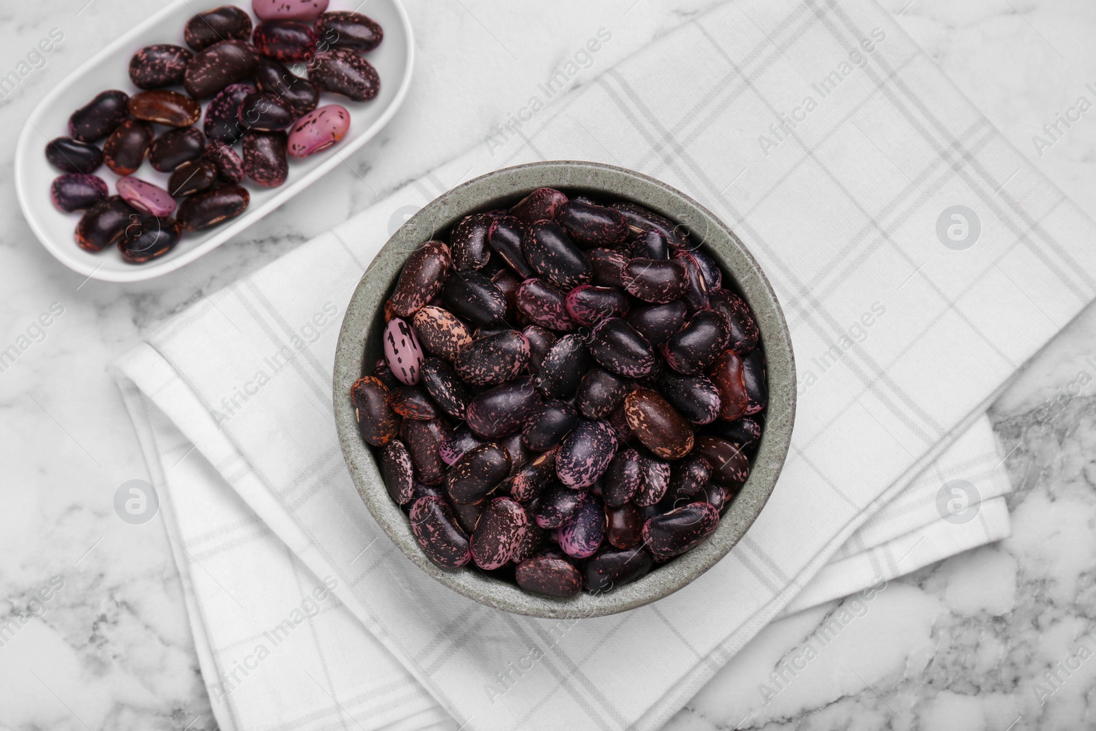 Photo of Bowls with dry kidney beans on white marble table, flat lay