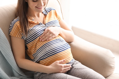 Photo of Young pregnant woman sitting on couch in living room