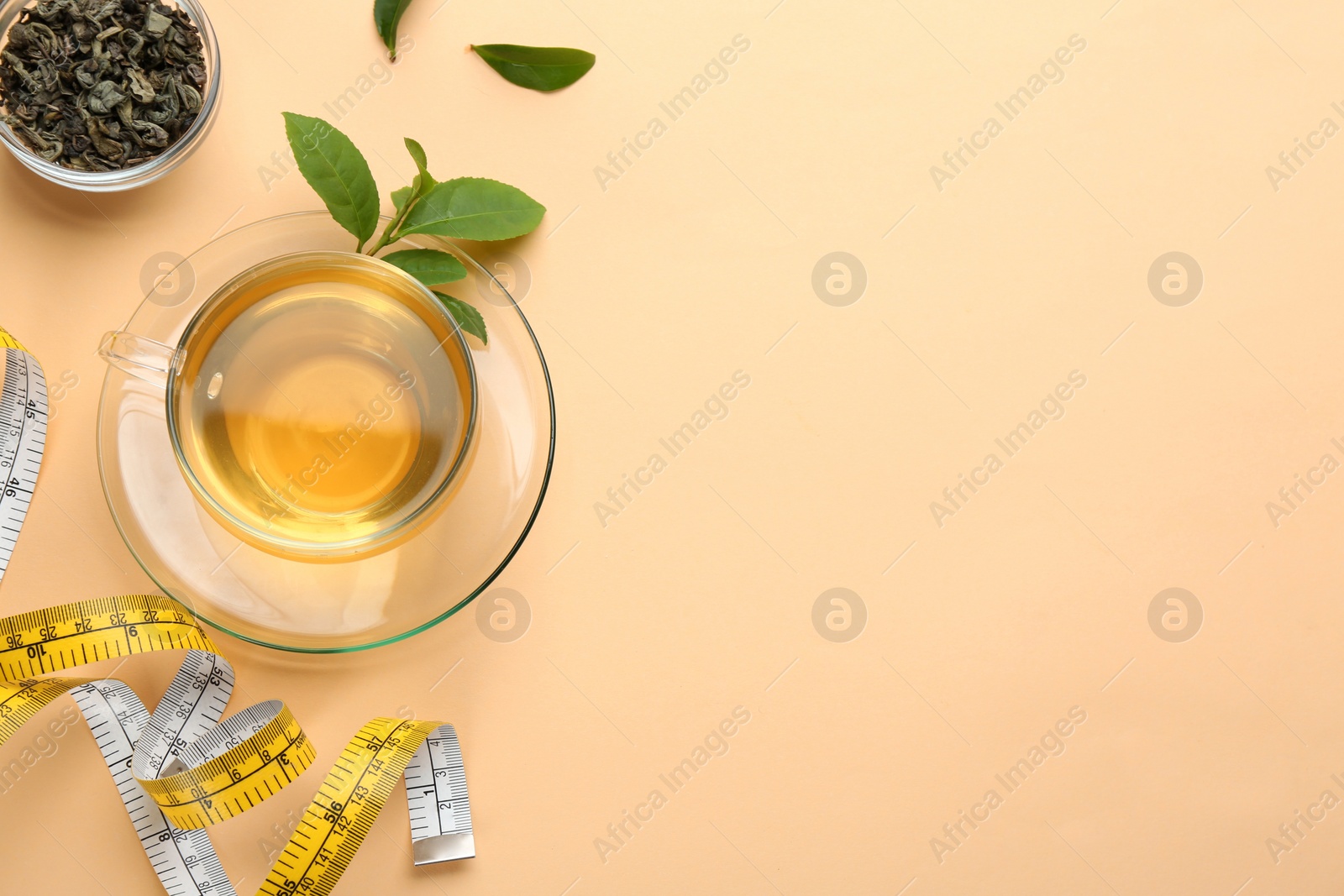 Photo of Flat lay composition with glass cup of diet herbal tea and measuring tape on orange background, space for text