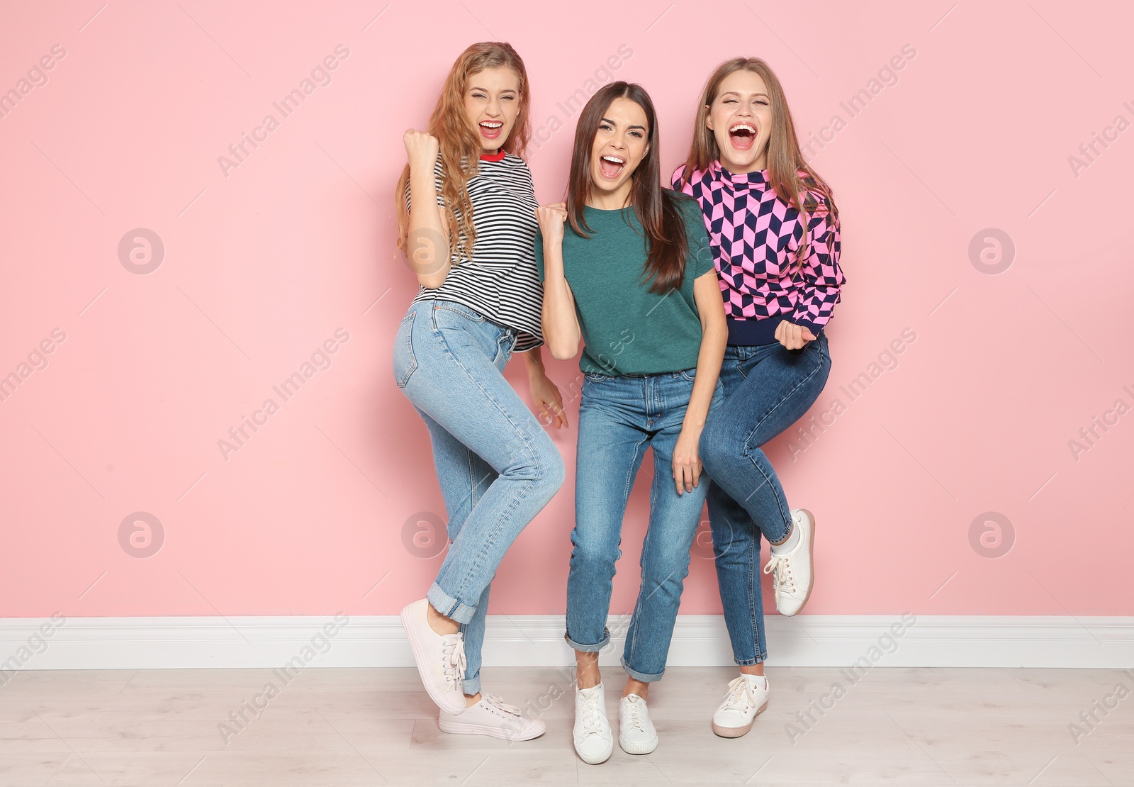 Photo of Young women celebrating victory near color wall