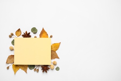 Flat lay composition with autumn leaves and blank card on white background, space for text