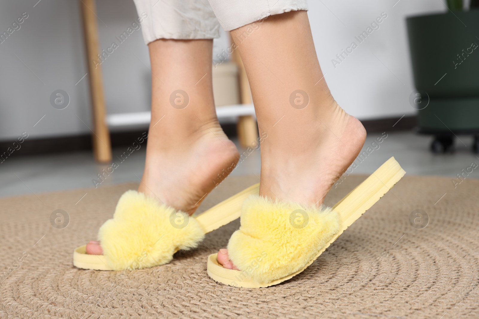 Photo of Woman wearing soft slippers at home, closeup of legs