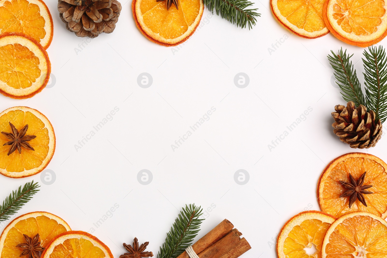 Photo of Frame made of dry orange slices, anise stars, fir branches and cones on white background, flat lay. Space for text