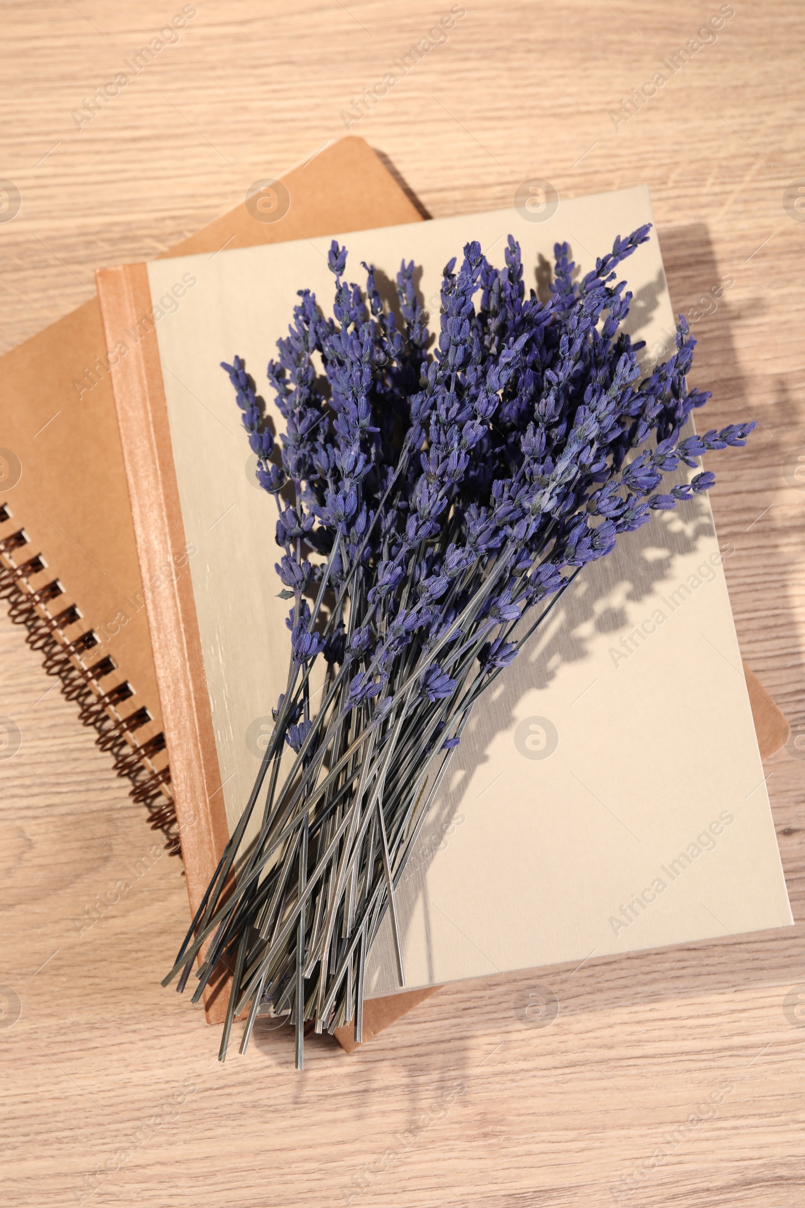 Photo of Bouquet of beautiful preserved lavender flowers and notebooks on wooden table, top view
